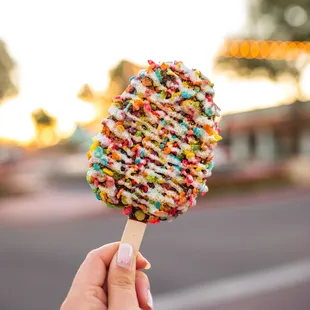 a hand holding an ice cream covered in sprinkles