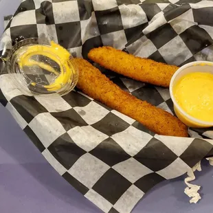 a basket of fried fish sticks with a side of mustard