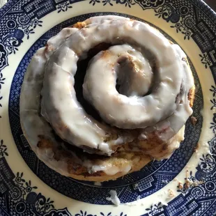 a glazed cinnamon roll on a blue and white plate