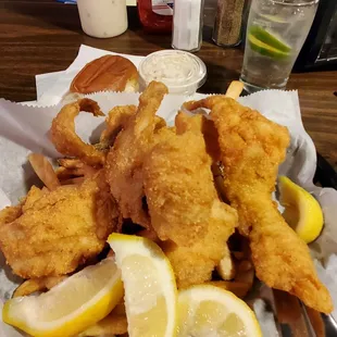 a basket of fried fish with lemon wedges