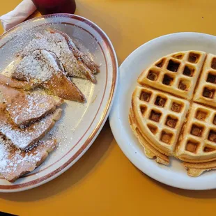 two plates of waffles with powdered sugar on them