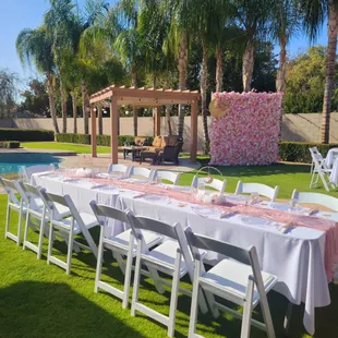 Emily Flower Wall, Long 6 ft. Tables, White Resin Chairs, and Blush/Pink Cheesecloth Table Runners.