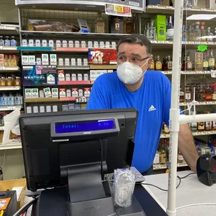 a man wearing a face mask behind a cash register