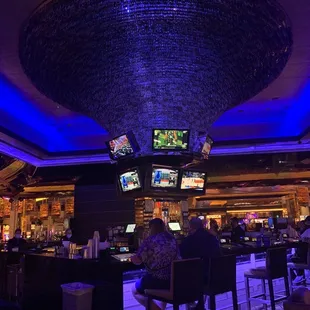 a man sitting at a bar watching tvs