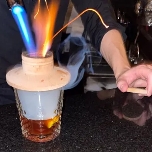 a man making a drink with a flame