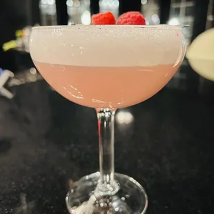 a pink cocktail with a raspberry garnish