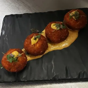 three appetizers on a black plate