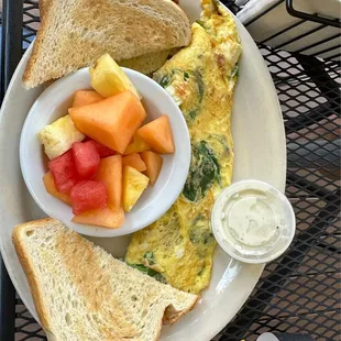 Spinach feta 3-egg omelette with sauce, fruit bowl and sourdough toast.