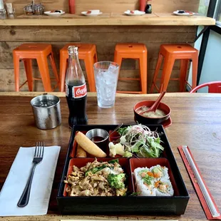 Chicken Bento Set featuring Miso Soup, Spicy Tuna Roll, Pad See Ew, Thai Rolls, Salad, and Coca-Cola.