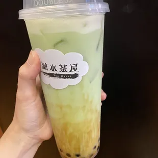 a hand holding a plastic cup of bubble tea