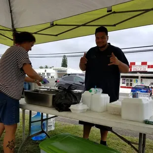 a man and a woman preparing food under a tent
