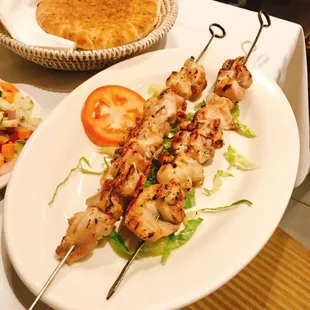 a plate of chicken skewers