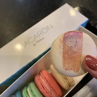 Half dozen macarons with chai chocolate being held up