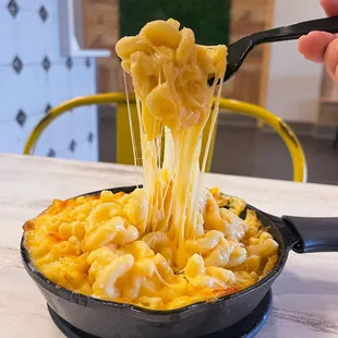a hand holding a fork full of macaroni and cheese