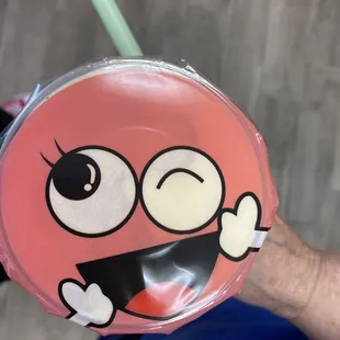 a close up of a person's hand holding a plastic cup with a smiley face on it