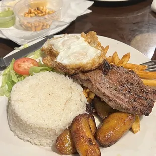 Steak, eggs, rice, fries, plantains and salad