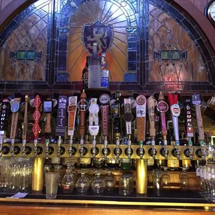 a row of beer taps in front of a stained glass window