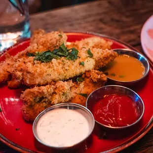 a plate of fried chicken with dipping sauces