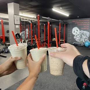 two people holding cups of coffee in a gym