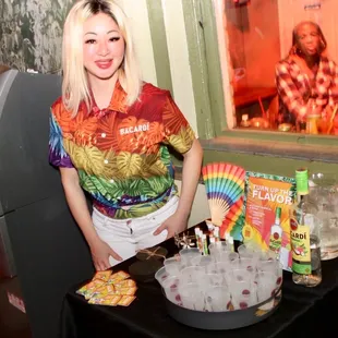 a woman standing in front of a table full of drinks