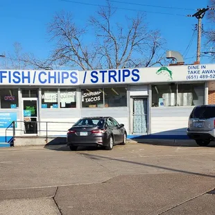 two cars parked in front of a shop