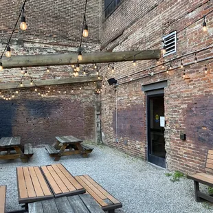 a patio with wooden benches and string lights