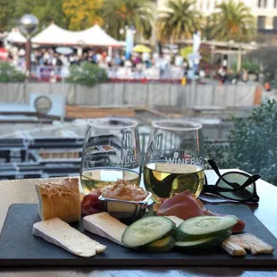 a cheese board with cheese, cucumbers, and bread