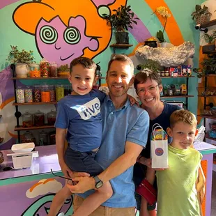 a family of three standing in front of a candy shop