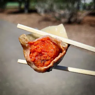 a dumpling with sauce and chopsticks