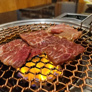 steaks cooking on a grill