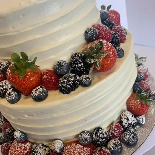 a three tiered cake with strawberries and blueberries