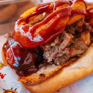 Texas Dog - 100% beef hot dog with pulled pork, BBQ sauce and Battered Onion Rings,