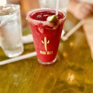 a red drink with a lime garnish