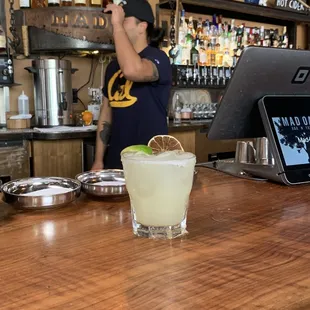 a man behind a bar with a glass of margarita