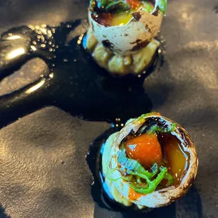 three sushi rolls on a black plate
