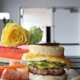 Egg and cheese breakfast sandwich, with sausage and avocado.