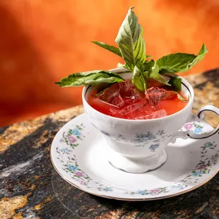 a cup of tea with ice cubes and a sprig of mint