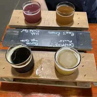 a flight of beers on a wooden tray