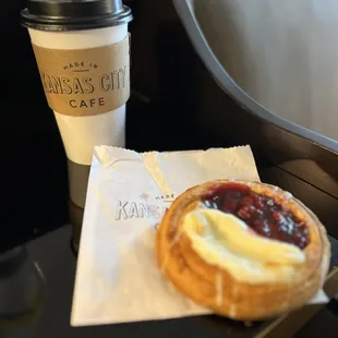 To-go coffee cup from Made in Kansas City Cafe with a berry-and-cream-cheese danish sitting on the pastry bag.