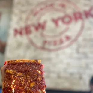 a hand holding a piece of pizza