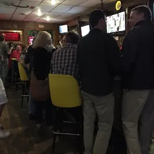people sitting at a bar watching televisions
