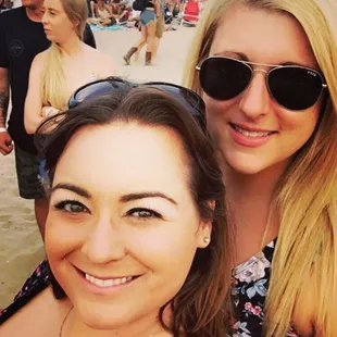 two women on the beach with a crowd of people in the background