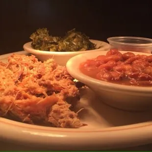 Pulled pork with side of BBQ sauce, fresh turnip greens, pinto beans.