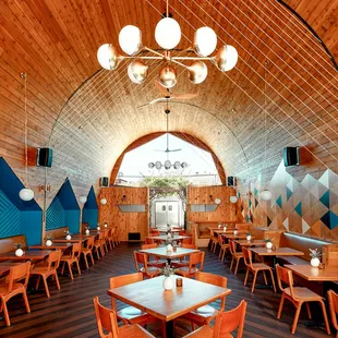 the interior of a restaurant with wooden tables and chairs