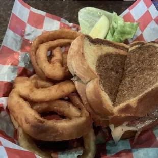 Maddy's Melt, a half pound burger with sautéed onions, Swiss and American cheese, on rye. Served with a pile of onion rings.