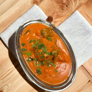 a plate of curry with a napkin on a wooden table