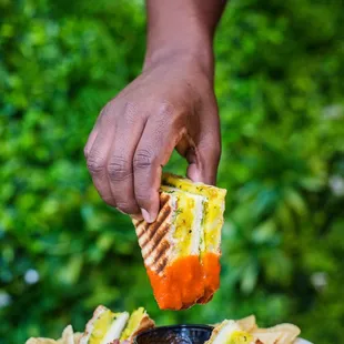 a person dipping a sandwich into a bowl of dip