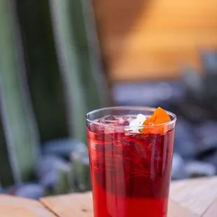 a glass of red drink on a wooden table