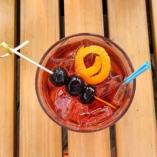 a drink with orange and black olives