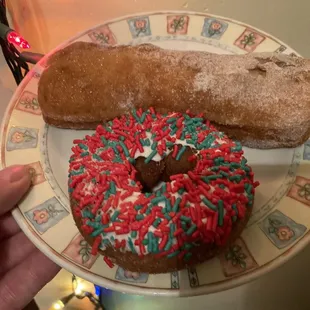 a hand holding a donut with sprinkles